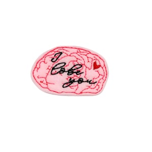 May include: Pink felt brain with red embroidered outline and the text "I love you" in black cursive. A small red heart is embroidered on the right side of the brain.