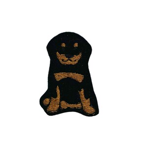May include: Black and brown embroidered patch of a dog sitting with its tongue out.