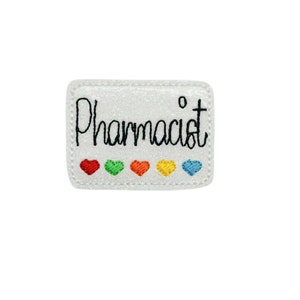 May include: White glitter iron-on patch with the word "Pharmacist" in black cursive lettering. Five small embroidered hearts in rainbow colors are below the text.