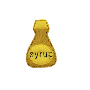 May include: A yellow felt toy shaped like a syrup bottle with the word "syrup" embroidered on the front.
