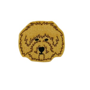 May include: A brown felt dog face patch with black embroidered eyes and nose.