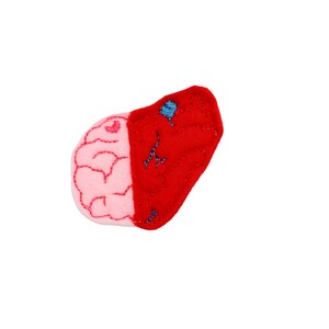 May include: A felt patch with an embroidered image of a brain and a heart. The brain is pink and the heart is red.