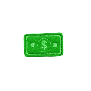May include: A green felt patch with a white embroidered dollar sign in the center. The patch has a stitched border.