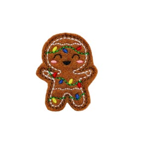 May include: A gingerbread man cookie with a happy face and colorful lights wrapped around it.