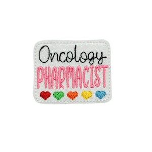 May include: White embroidered patch with the text "Oncology Pharmacist" in pink and black lettering. Five small rainbow hearts are below the text.