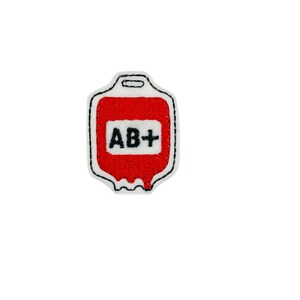 May include: Red embroidered blood bag patch with white outline and black text that reads "AB+"