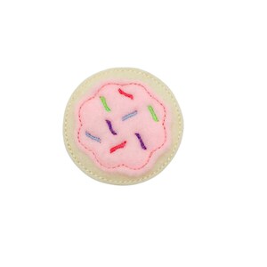 May include: A pink and white felt cookie with colorful sprinkles. The cookie is a felt applique and is perfect for a craft project or a child's play.