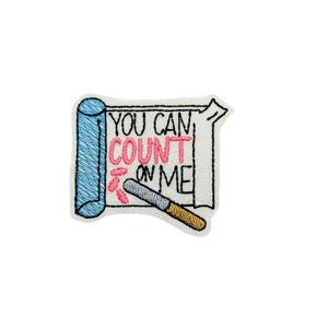 May include: Embroidered iron-on patch with a white background and a blue and white rolled up paper with the text "YOU CAN COUNT ON ME" written in black and pink. A gray and gold pencil is drawn on the paper.