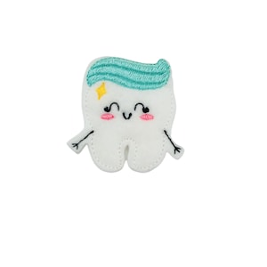 May include: A white felt tooth with a blue and green toothpaste design on top. The tooth has a happy face with pink cheeks and yellow star.