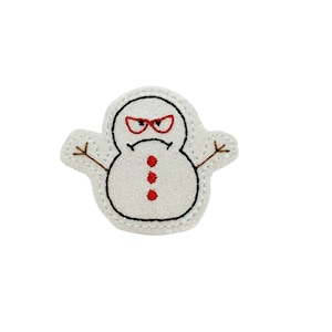 May include: A white felt snowman with red eyes, a red frown, and three red buttons. The snowman has brown twig arms.