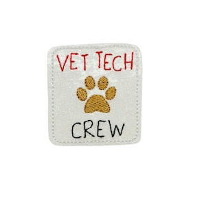 May include: White square patch with red embroidered text "VET TECH" and black embroidered text "CREW". A gold embroidered paw print is centered between the text.