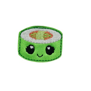 May include: A green and white embroidered sushi roll with a cute cartoon face. The sushi roll has a smiling mouth and large black eyes.