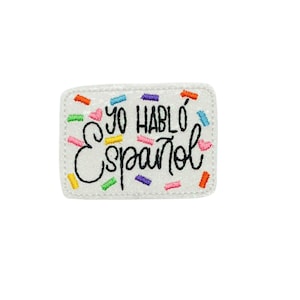 May include: White embroidered patch with the text "Yo Hablo Espanol" in black script. The patch is decorated with colorful confetti-like sprinkles.