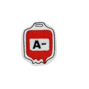 May include: Red embroidered blood bag patch with white stitching and black outline. The bag has a label with the text "A-" in black.