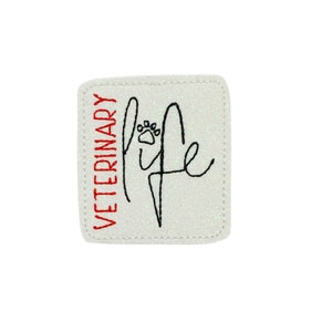 May include: A square, glittery white patch with the words "VETERINARY" in red and "life" in black script, featuring a paw print. The patch has a white border.