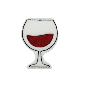 May include: A red wine glass with a black outline, embroidered on a white fabric.
