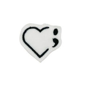 May include: White felt patch with a black outline of a heart and a semicolon inside the heart.