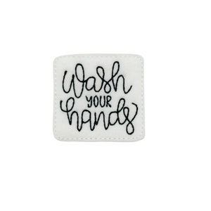 May include: White felt square with black embroidered text that reads "Wash your hands".