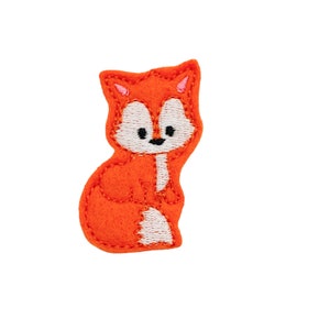 May include: An orange fox patch with white and black details. The embroidered patch features a cartoon fox sitting upright, with a white chest and belly, and black eyes. The fox has a small black nose and a white muzzle.