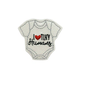 May include: White glitter iron-on patch shaped like a baby onesie with the text "I love tiny humans" and a red heart.
