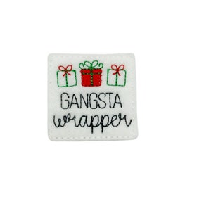 May include: White felt square with three embroidered Christmas presents and the text "GANGSTA wrapper" in black thread.