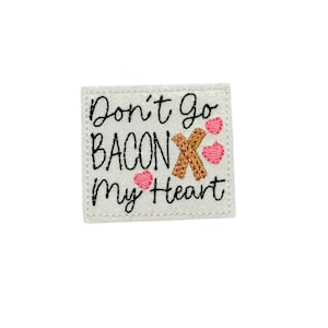 May include: White glitter iron-on patch with black text that reads "Don't go bacon my heart" with a gold X and pink hearts.