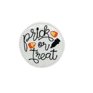 May include: White circle with a glittery surface and black text that says "trick or treat". There are two orange and yellow candy corn and a black silhouette of a ghost.