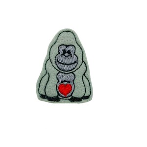 May include: A gray felt applique of a gorilla holding a red heart.