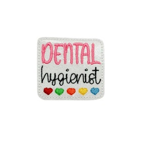 May include: White embroidered patch with pink text that reads "DENTAL hygienist".  Five small hearts in rainbow colors are below the text.