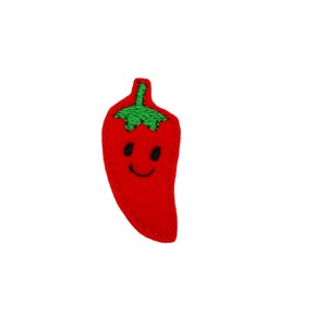 May include: A red felt chili pepper with a green stem and a smiling face embroidered on it.