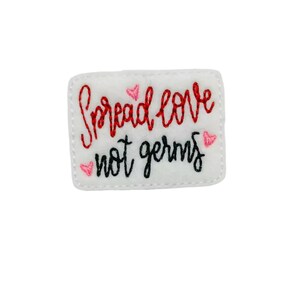May include: White felt patch with red embroidered text "Spread love not germs" and pink embroidered hearts.