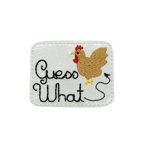 May include: White glitter iron-on patch with black embroidery that says "Guess What's" and a brown chicken with a red comb and yellow feet.