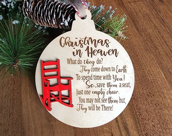 May include: Wooden Christmas ornament with the text "Christmas in Heaven" and a red rocking chair. The ornament includes a poem about loved ones. The ornament is round with a hole for hanging.