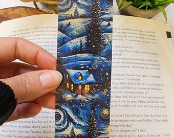 May include: A blue and white bookmark with a winter scene featuring a house with a lit window, a snowy landscape, and a tall pine tree with a star on top. The background is a starry night sky.