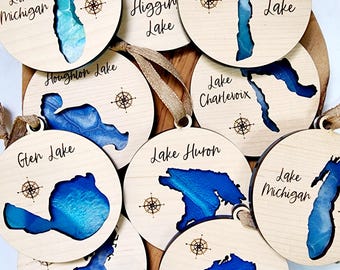 Puede incluir: Un conjunto de diez adornos de madera que representan diferentes lagos de Michigan. Cada adorno está pintado con acuarelas azules y blancas y tiene el nombre del lago escrito en él. Los adornos son perfectos para decorar un árbol de Navidad o agregar un toque de orgullo de Michigan a tu hogar.