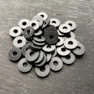 May include: A pile of black rubber washers. The washers are round with a hole in the center.