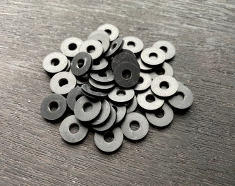 May include: A pile of black rubber washers. The washers are round with a hole in the center.