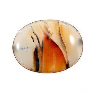 May include: Oval-shaped agate stone with a polished surface. The stone features a blend of colors, including orange, black, and cream, with a metallic border. The design resembles a flame or abstract landscape. The agate is a natural gemstone.