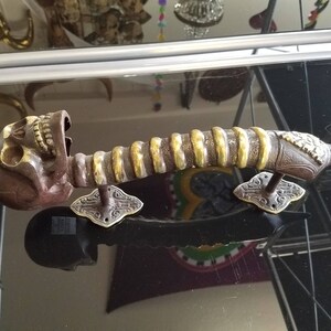 May include: A decorative door handle with a skull design and a gold and silver finish. The handle is made of metal and has a unique, ornate design.
