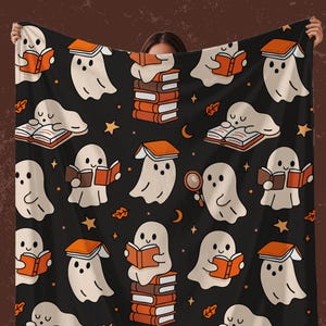 Peut inclure: Couverture noire avec un motif répété de fantômes de dessins animés lisant des livres. Les livres ont des couvertures orange, et le motif comprend des étoiles, des lunes et des feuilles. Le texte "Shadowbound Spines+" est en bas.