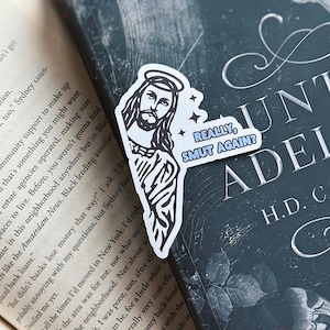 May include: A white sticker with a black and white illustration of Jesus with a halo. The sticker has the text "REALLY, SMUT AGAIN?" in blue and white.