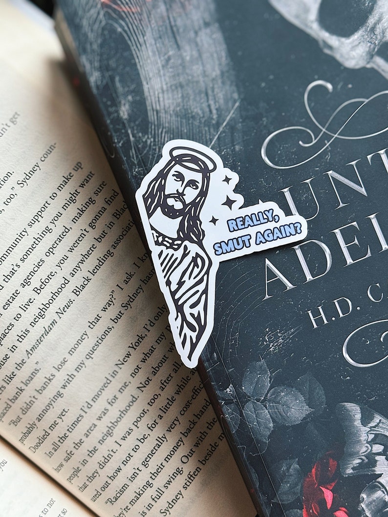 May include: A white sticker with a black and white illustration of Jesus with a halo. The sticker has the text "REALLY, SMUT AGAIN?" in blue and white.