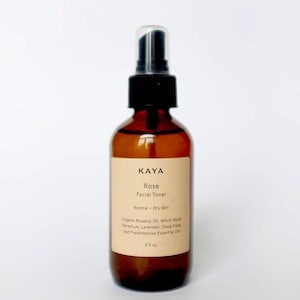 Puede incluir: Una botella de vidrio marrón con un pulverizador negro, etiquetada "KAYA Rose Facial Toner Normal - Dry Skin Organic Rosehip Oil, Witch Hazel, Geranium, Lavender, Ylang Ylang and Frankincense Essential Oils 4 fl oz"