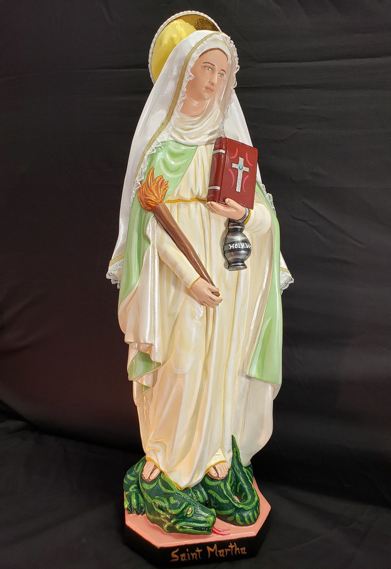 Pu&ograve; includere: Statua di Santa Marta, raffigurata in una veste bianca e verde fluente, con una torcia e un libro rosso con una croce. Si trova su una base di drago verde, con il nome "Saint Martha" inciso.