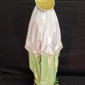 Pu&ograve; includere: Statua religiosa di una figura che indossa un velo di raso bianco e un'aureola dorata. La veste della figura &egrave; verde chiaro con accenti dorati. La base &egrave; nera con la scritta "July 29".