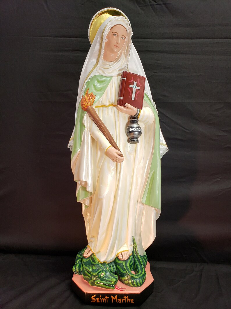 Pu&ograve; includere: Statua di Santa Marta, raffigurata in abiti bianchi e verdi, con in mano una torcia, un libro e una lanterna. La statua poggia su una base con un drago verde. La base recita "Saint Martha".