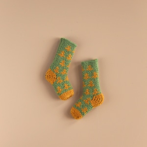 May include: A pair of green socks with a yellow star pattern. The socks are knitted and have a ribbed texture.