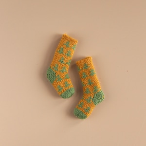May include: A pair of yellow and green knitted socks with a geometric pattern.