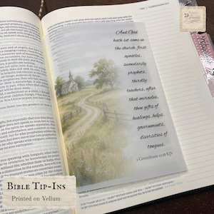 Puede incluir: Un inserto de vitela translúcido colocado dentro de una Biblia abierta, con una ilustración impresa de una iglesia rural con un camino sinuoso y el texto: And God hath set some in the church, first apostles, secondarily prophets.