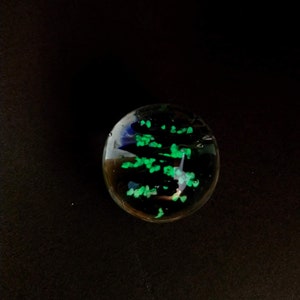 May include: A clear glass paperweight with green and blue glitter inside.